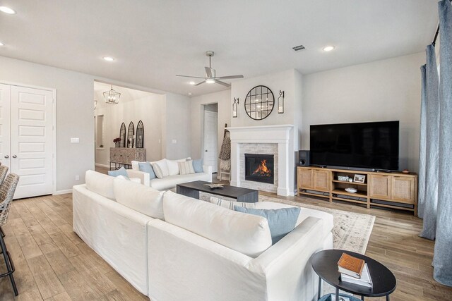 living area with recessed lighting, baseboards, a stone fireplace, and wood finished floors