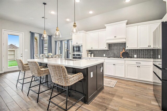 kitchen with backsplash, appliances with stainless steel finishes, white cabinets, and light countertops