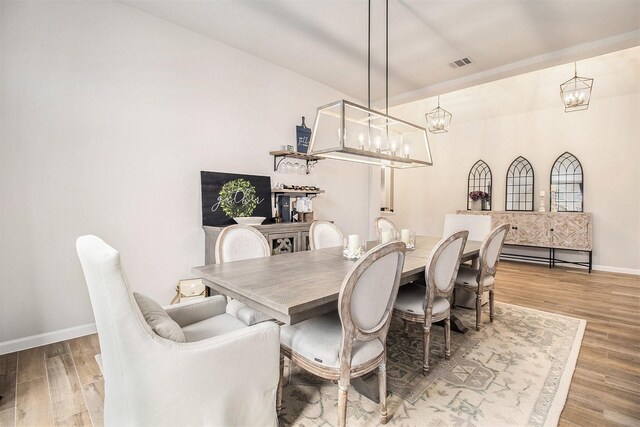 dining area featuring visible vents, baseboards, wood finished floors, and a chandelier