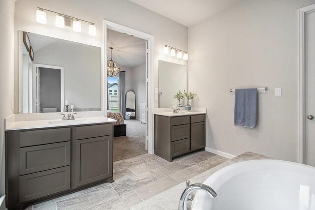 ensuite bathroom featuring two vanities, a tub, a sink, ensuite bathroom, and a chandelier