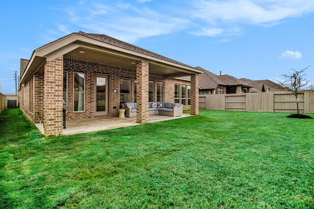 rear view of property featuring outdoor lounge area, a patio area, brick siding, and a fenced backyard