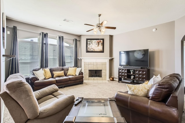 living area featuring visible vents, a tiled fireplace, arched walkways, carpet, and ceiling fan