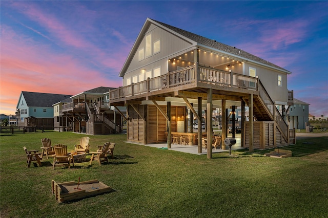 back of property at dusk with stairway, an outdoor fire pit, a yard, a deck, and a patio area