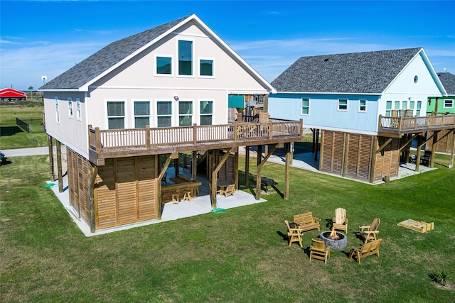 back of house with a patio, an outdoor fire pit, a yard, roof with shingles, and a wooden deck