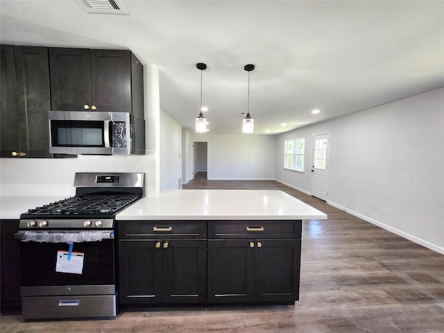 kitchen featuring wood finished floors, visible vents, a peninsula, stainless steel appliances, and light countertops