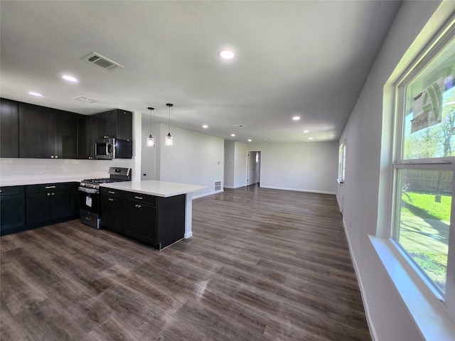 kitchen with visible vents, dark wood-style flooring, stainless steel appliances, light countertops, and open floor plan