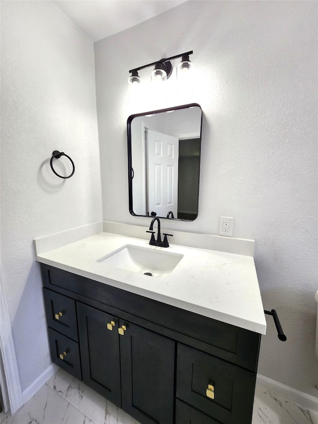 bathroom with marble finish floor, vanity, and baseboards