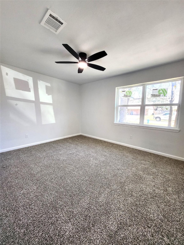 spare room featuring baseboards, visible vents, and dark carpet