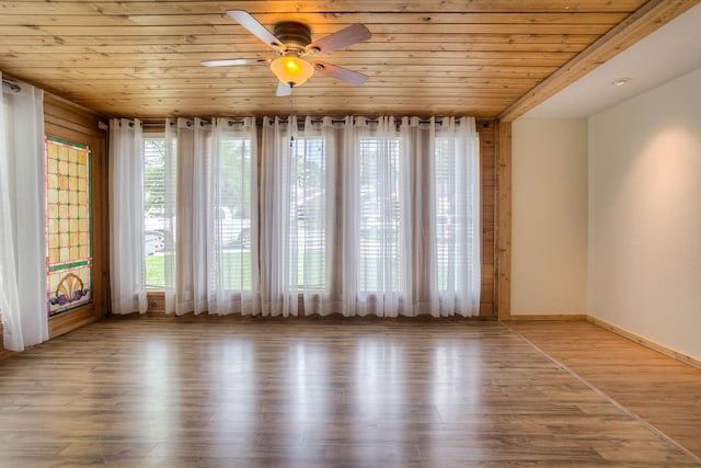 empty room with baseboards, wood finished floors, wooden ceiling, and a ceiling fan