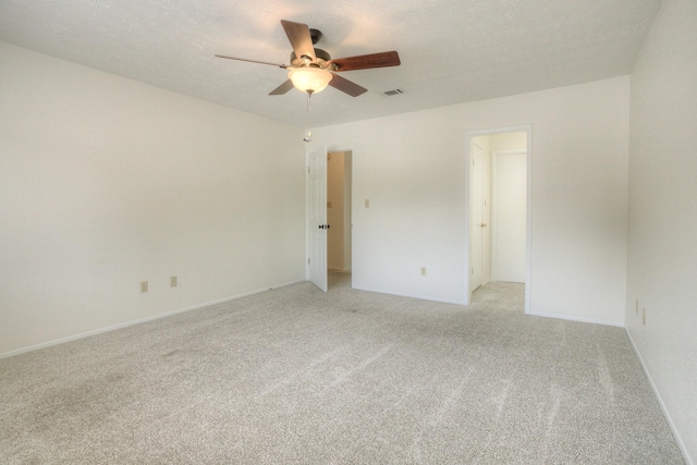 unfurnished room with ceiling fan, light colored carpet, visible vents, and a textured ceiling