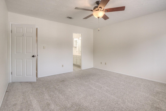 unfurnished bedroom with light carpet, ensuite bathroom, a ceiling fan, a textured ceiling, and baseboards