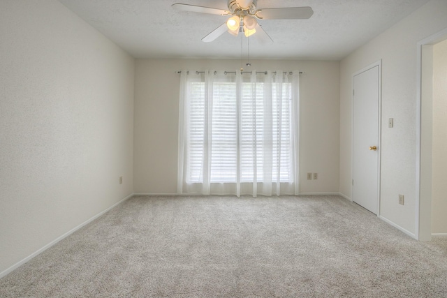 carpeted empty room featuring baseboards, a textured ceiling, and ceiling fan