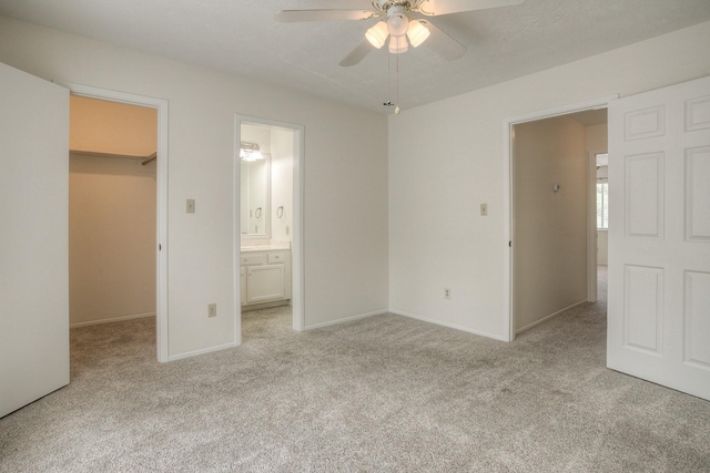 unfurnished bedroom with a spacious closet, baseboards, a closet, and light carpet