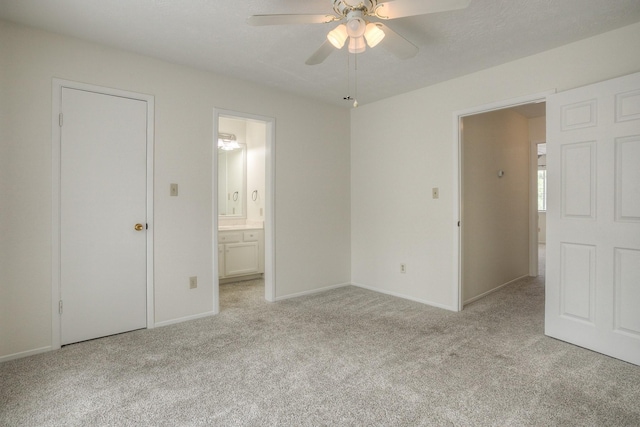 unfurnished bedroom featuring baseboards, light carpet, a ceiling fan, and ensuite bathroom