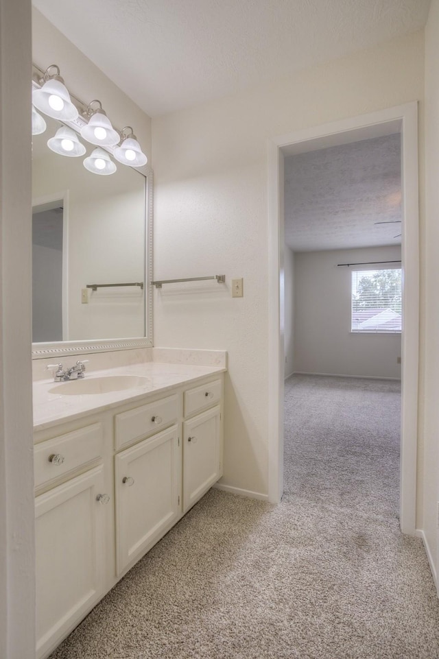 bathroom featuring baseboards, a textured ceiling, vanity, and carpet