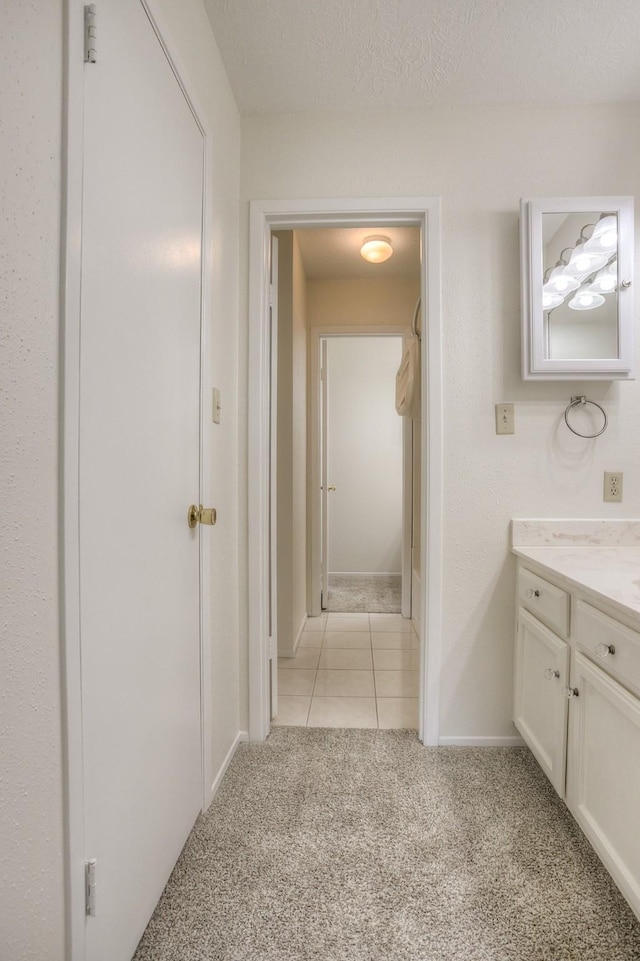 bathroom featuring baseboards, vanity, carpet flooring, tile patterned floors, and a textured ceiling