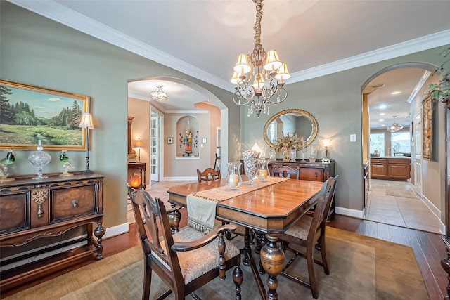 dining space with arched walkways, baseboards, crown molding, and light wood-style floors