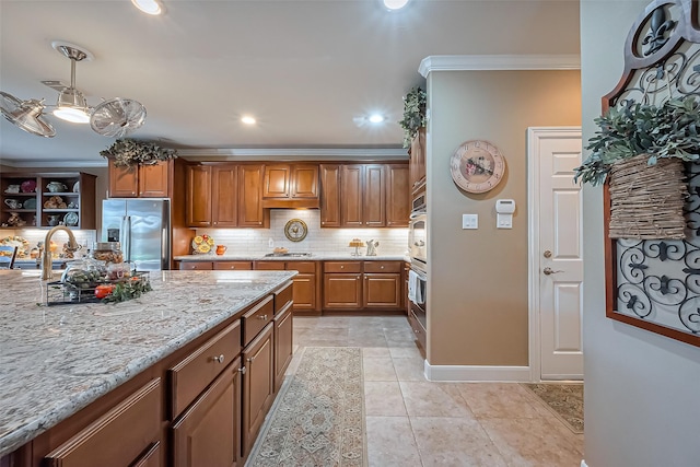 kitchen featuring crown molding, backsplash, brown cabinets, and appliances with stainless steel finishes