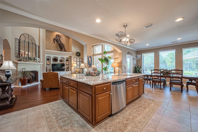 kitchen with visible vents, crown molding, light stone counters, stainless steel dishwasher, and a sink