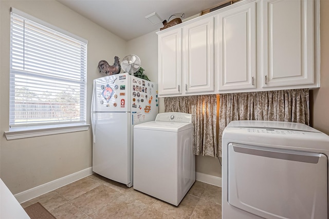 clothes washing area with cabinet space, washing machine and dryer, and baseboards