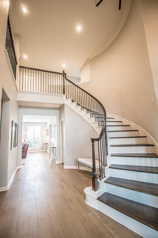 staircase featuring recessed lighting, a high ceiling, baseboards, and wood finished floors