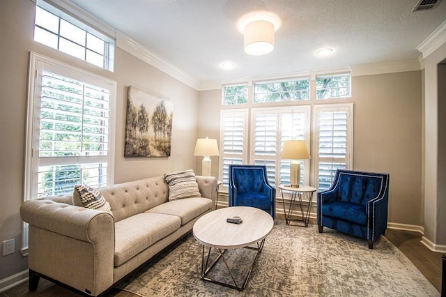 living area featuring visible vents, baseboards, ornamental molding, wood finished floors, and a textured ceiling