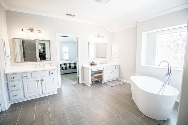 ensuite bathroom featuring visible vents, connected bathroom, a freestanding bath, ornamental molding, and two vanities