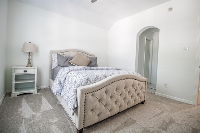 carpeted bedroom featuring baseboards, arched walkways, and vaulted ceiling