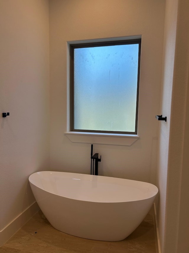 bathroom featuring a freestanding tub and baseboards