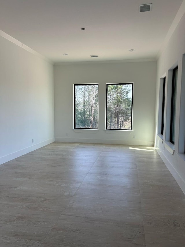 unfurnished room featuring baseboards, visible vents, and ornamental molding