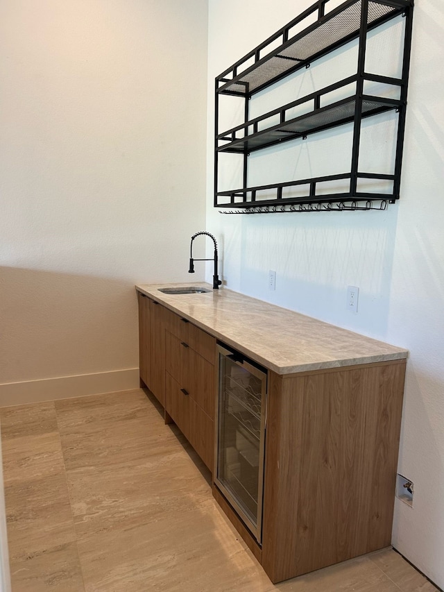 bar with a sink, baseboards, wine cooler, and indoor wet bar