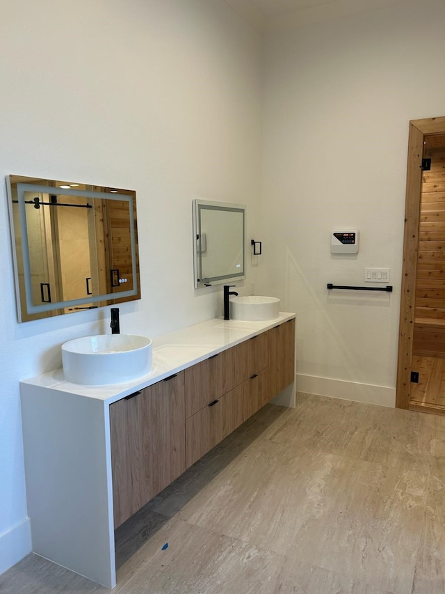 full bath featuring double vanity, baseboards, and a sink