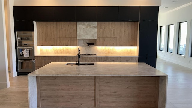 kitchen featuring decorative backsplash, a center island with sink, modern cabinets, and dark cabinetry