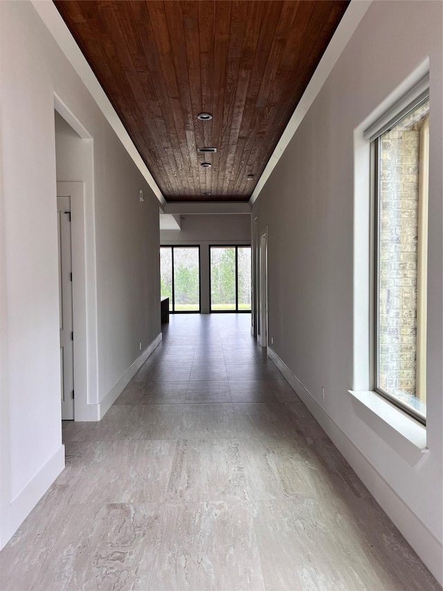 hallway featuring baseboards and wooden ceiling