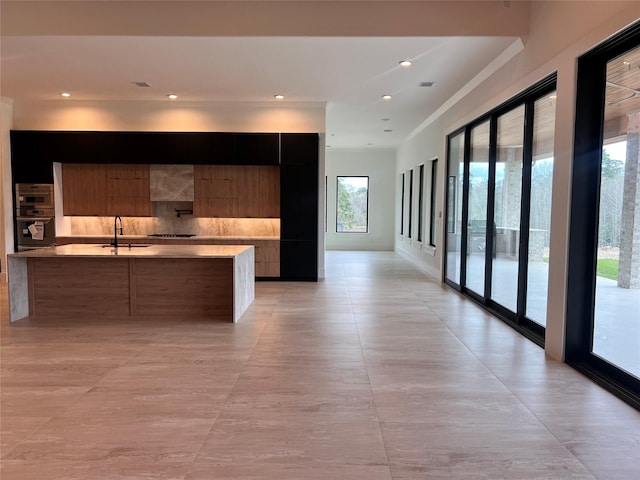 kitchen featuring backsplash, light countertops, stainless steel appliances, modern cabinets, and a sink