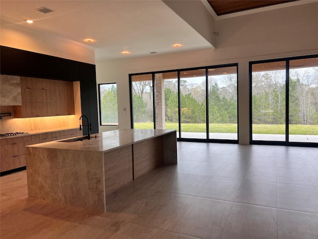 kitchen with visible vents, a sink, gas stovetop, modern cabinets, and a kitchen island with sink