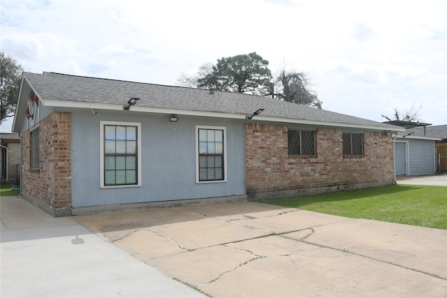 view of front facade featuring concrete driveway, brick siding, and a shingled roof