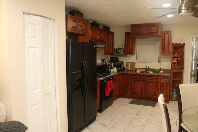 kitchen featuring range with gas stovetop, a ceiling fan, under cabinet range hood, marble finish floor, and black fridge