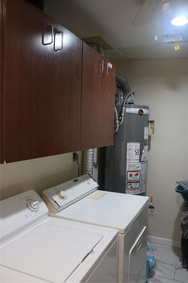 laundry area featuring baseboards, washing machine and clothes dryer, cabinet space, gas water heater, and marble finish floor