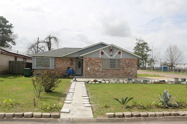 view of front of house featuring brick siding, a front yard, and fence