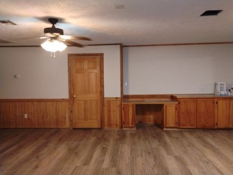 unfurnished living room featuring a wainscoted wall, light wood finished floors, and built in study area