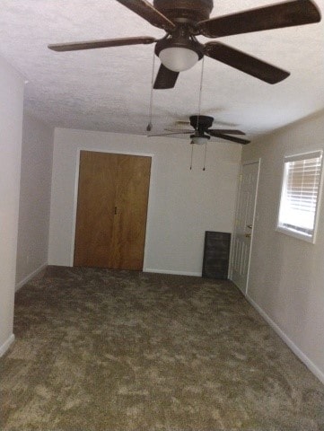 carpeted spare room featuring a ceiling fan, baseboards, and a textured ceiling