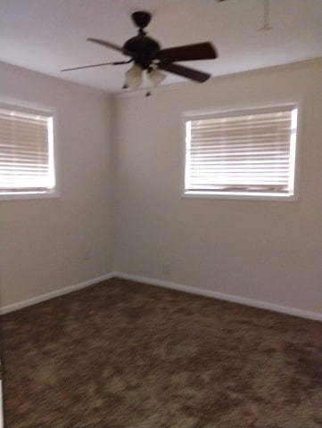 unfurnished room with dark colored carpet, baseboards, and a ceiling fan