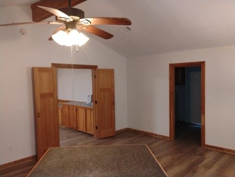 empty room featuring visible vents, ceiling fan, baseboards, vaulted ceiling, and wood finished floors