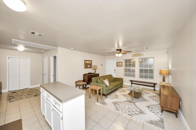 living room with visible vents, baseboards, attic access, light tile patterned flooring, and a ceiling fan