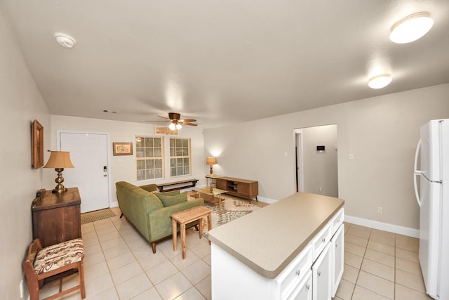 living area with light tile patterned floors, a ceiling fan, and baseboards