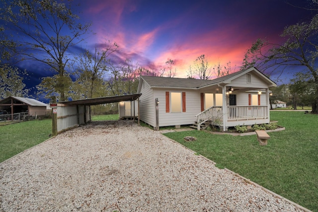 ranch-style home featuring a detached carport, a ceiling fan, fence, gravel driveway, and a front lawn