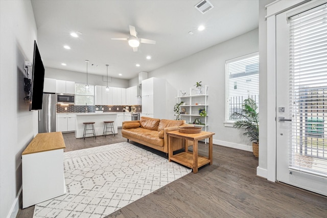 living room featuring a ceiling fan, dark wood-style floors, visible vents, baseboards, and recessed lighting