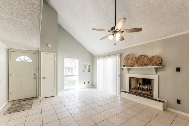 tiled foyer entrance with a textured ceiling, lofted ceiling, a fireplace with raised hearth, and ceiling fan