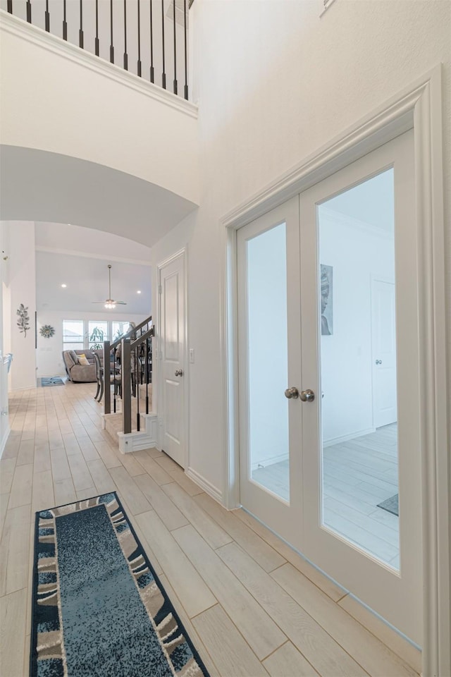 interior space with stairs, french doors, a towering ceiling, and wood finish floors